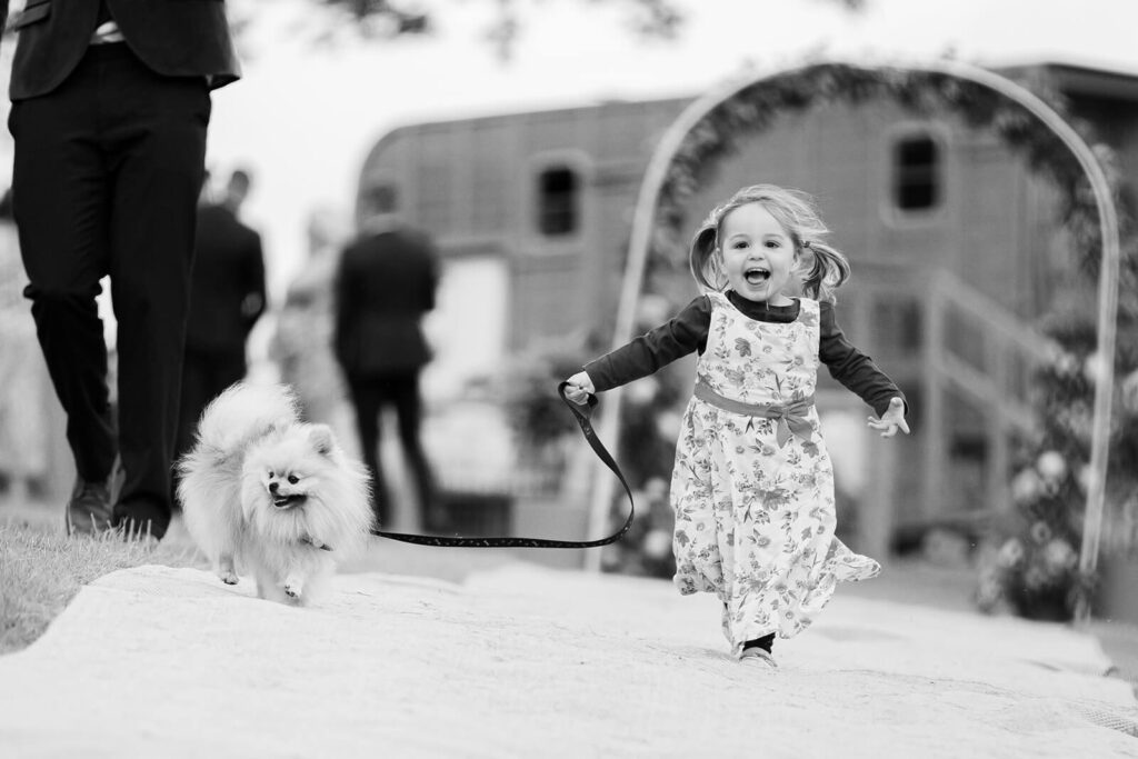 little girl running down a path excitedly leading a little dog 