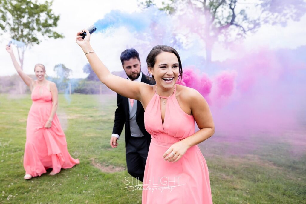 bridesmaid in link dress laughing holding blue smoke grenade