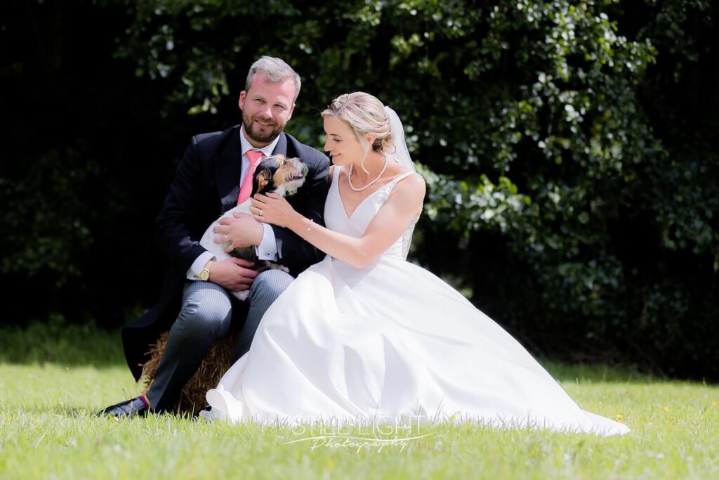bride and groom sitting with their jack russel dog on wedding day