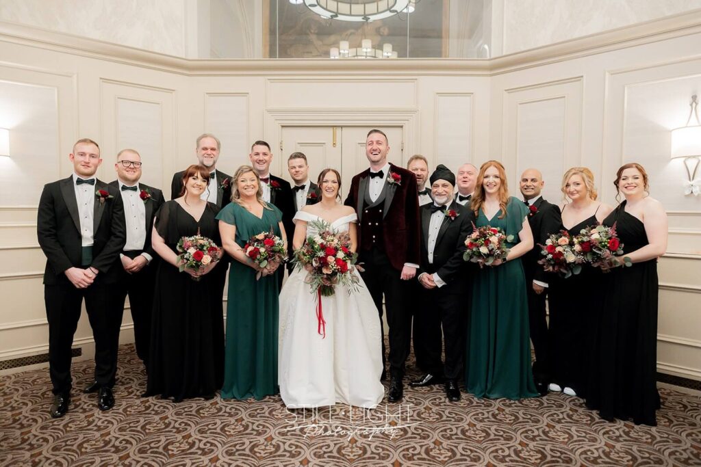 wedding group photographs with men in tuxedos and ladies in black and green dresses
