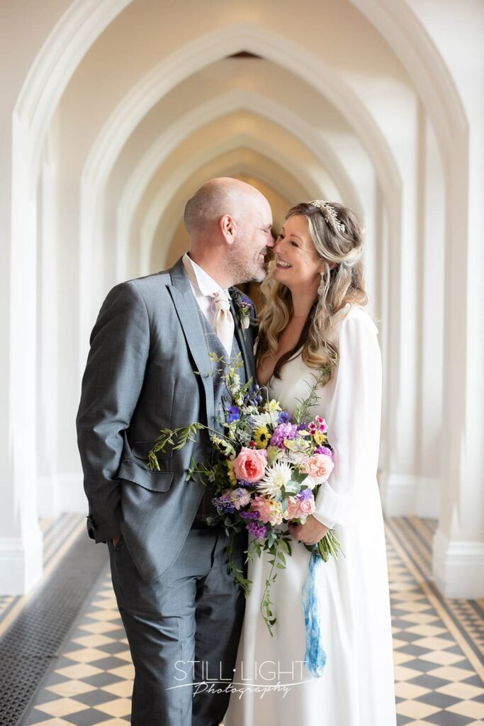bride and groom close laughing indoor in cloisters at stanbrook abbey