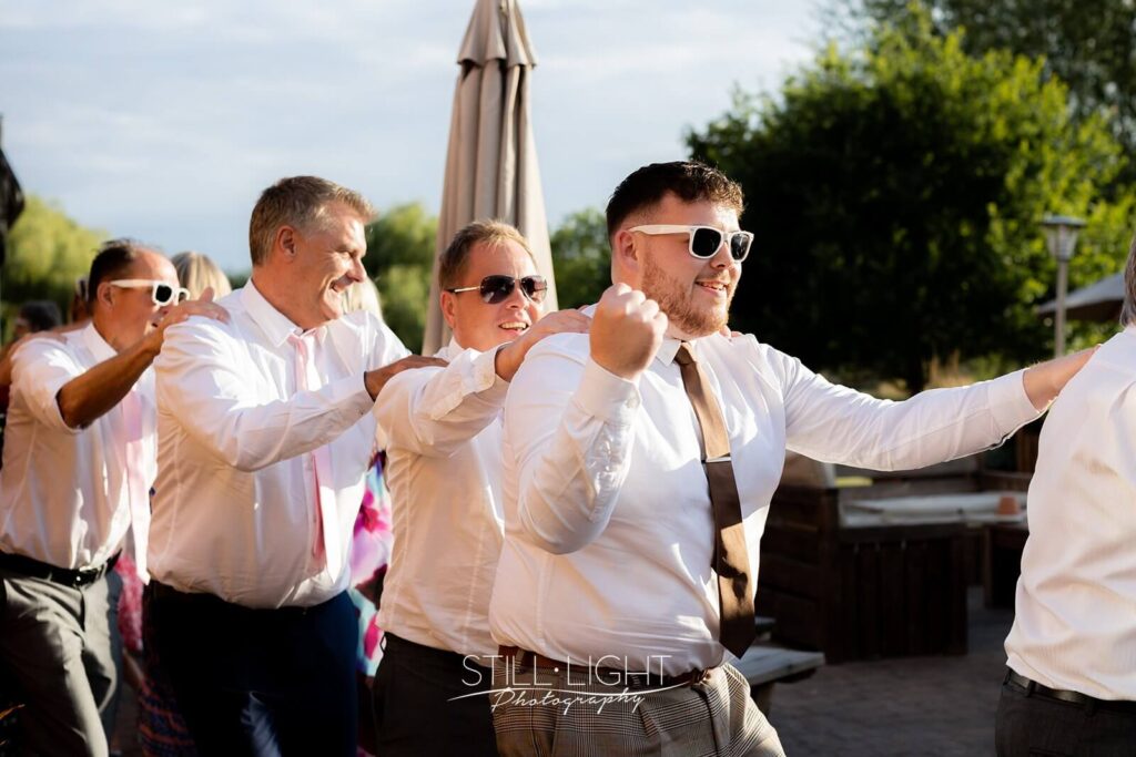 wedding guests doing a conga line during singing waiter performance at wootton park