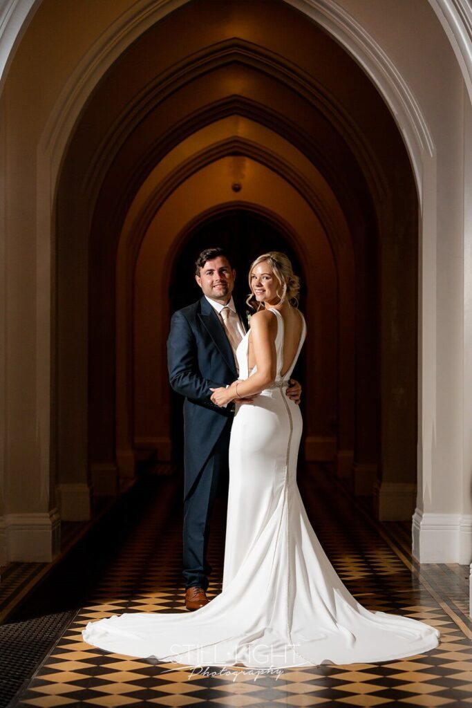 bride and groom dramatically lit standing indoor in cloisters at stanbrook abbey