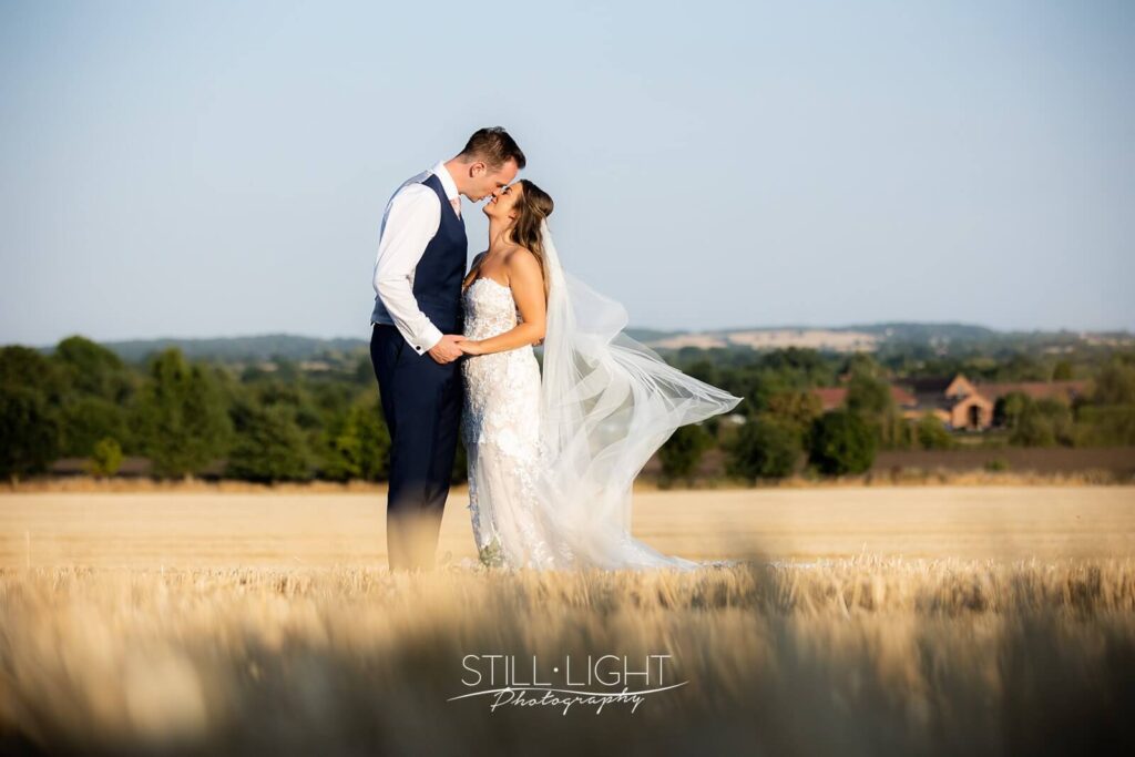 bride and groom kissing in field during estate tour at wootton park