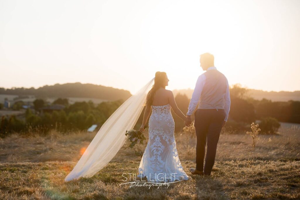 bride and groom facing away from camera into the sunset during estate tour at wootton park