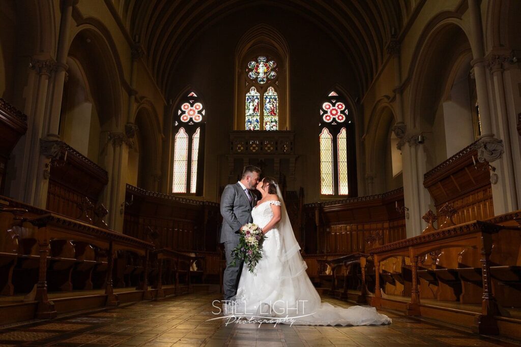 bride and groom kissing standing in Callow Great Hall at Stanbrook Abbey with spotlight hitting them