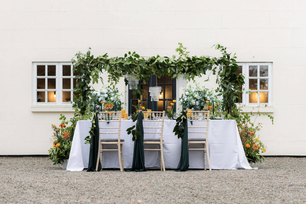 small dinner table set up outside in the courtyard at the hopton court coach house with foliage surrounding the table
