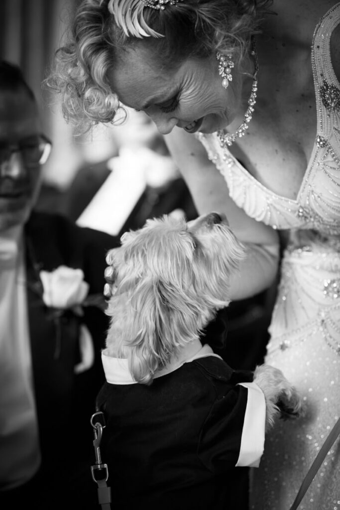 bride dressed in vintage dress leaning down to greet her dog on wedding day