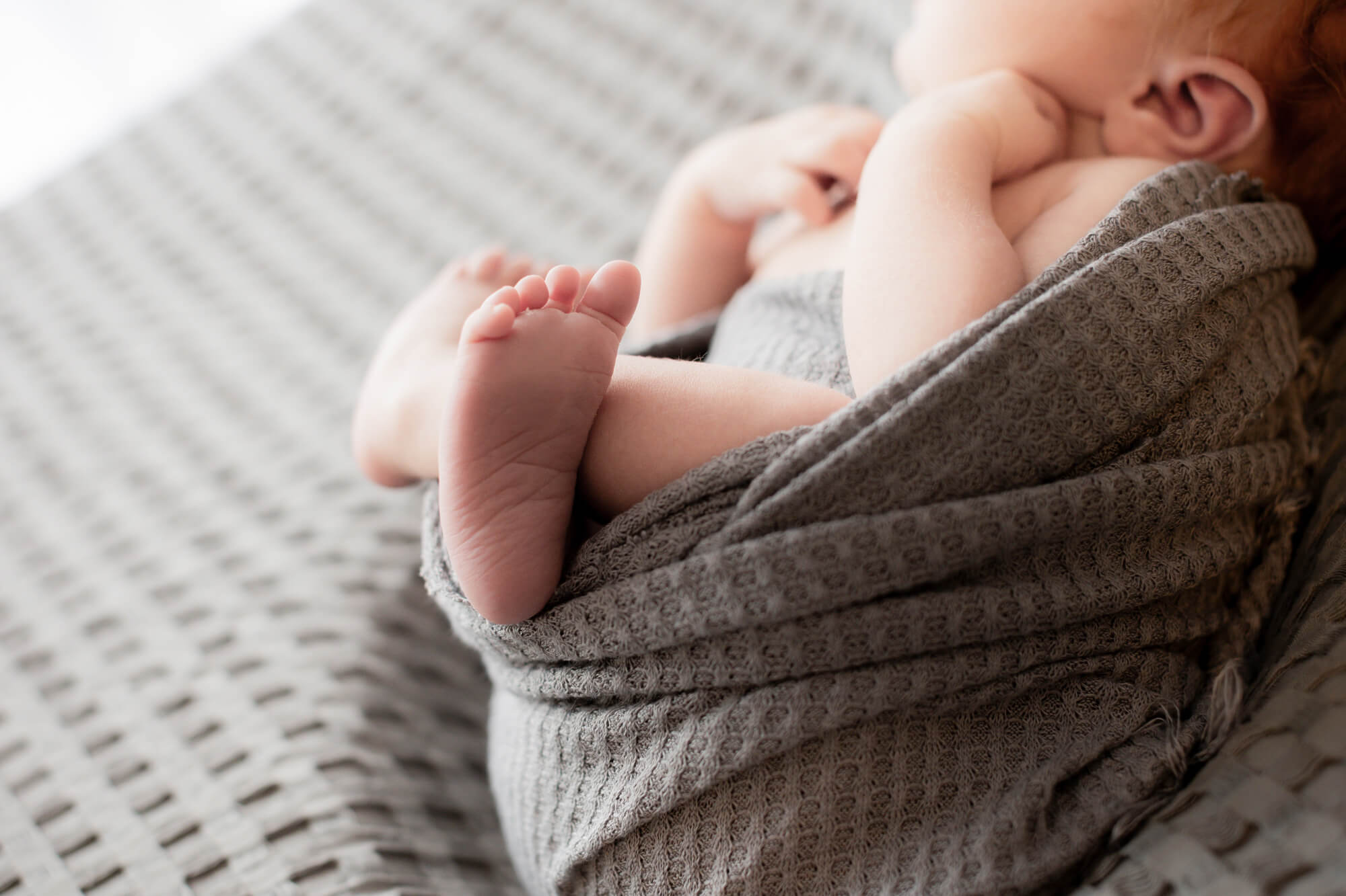 newborn baby feet wrapped in grey blanket